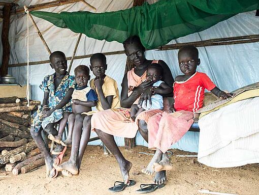 Eine Mutter mit ihren fünf Kindern sitzt auf einem Feldbett in einer Flüchtlingsunterkunft in Juba, Südsudan.